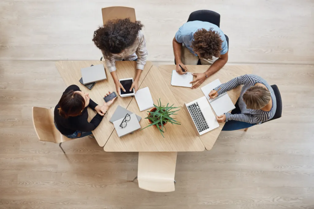 Personas trabajando en un coworking en una mesa de madera