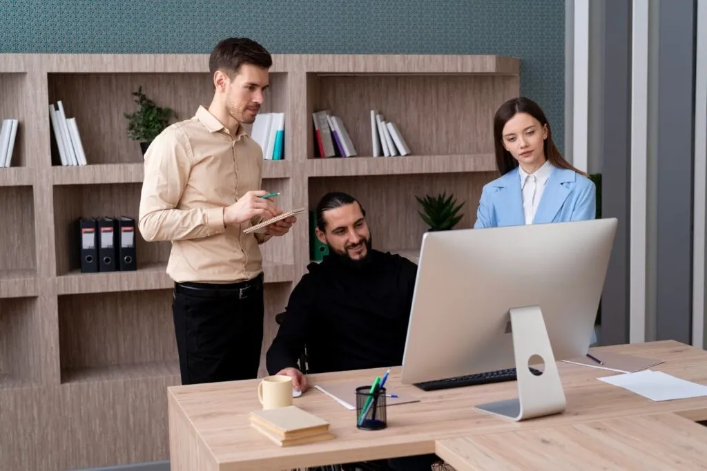 Tres personas en una oficina privada viendo una computadora.